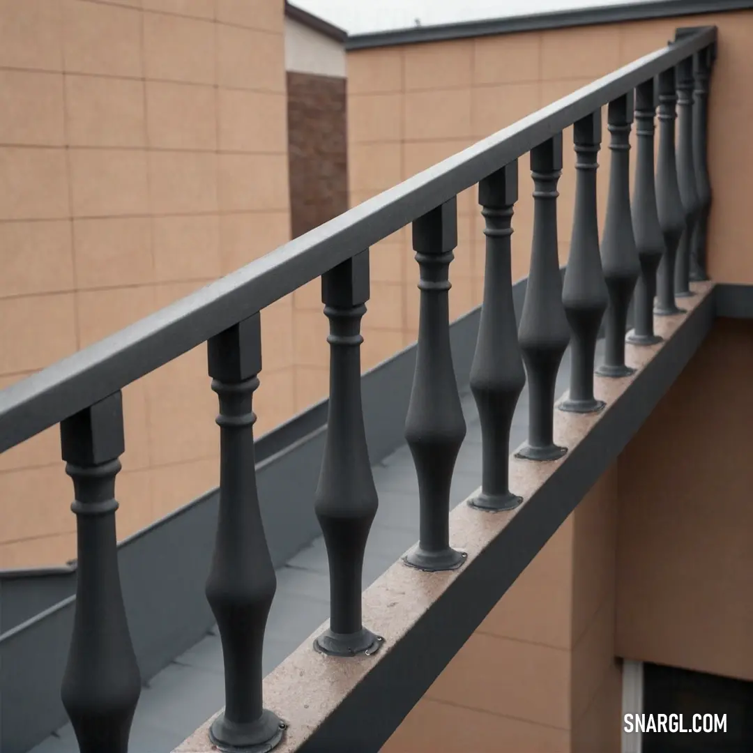 A sleek metal railing with black posts lines the edge of a modern building, contrasting with its simple, industrial design. The background shows a distant structure, adding depth to the overall composition.