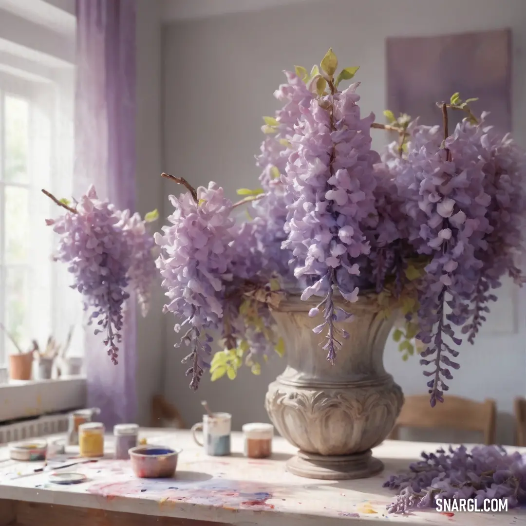 Vase filled with purple flowers on top of a table next to a window with purple curtains and a painting palette