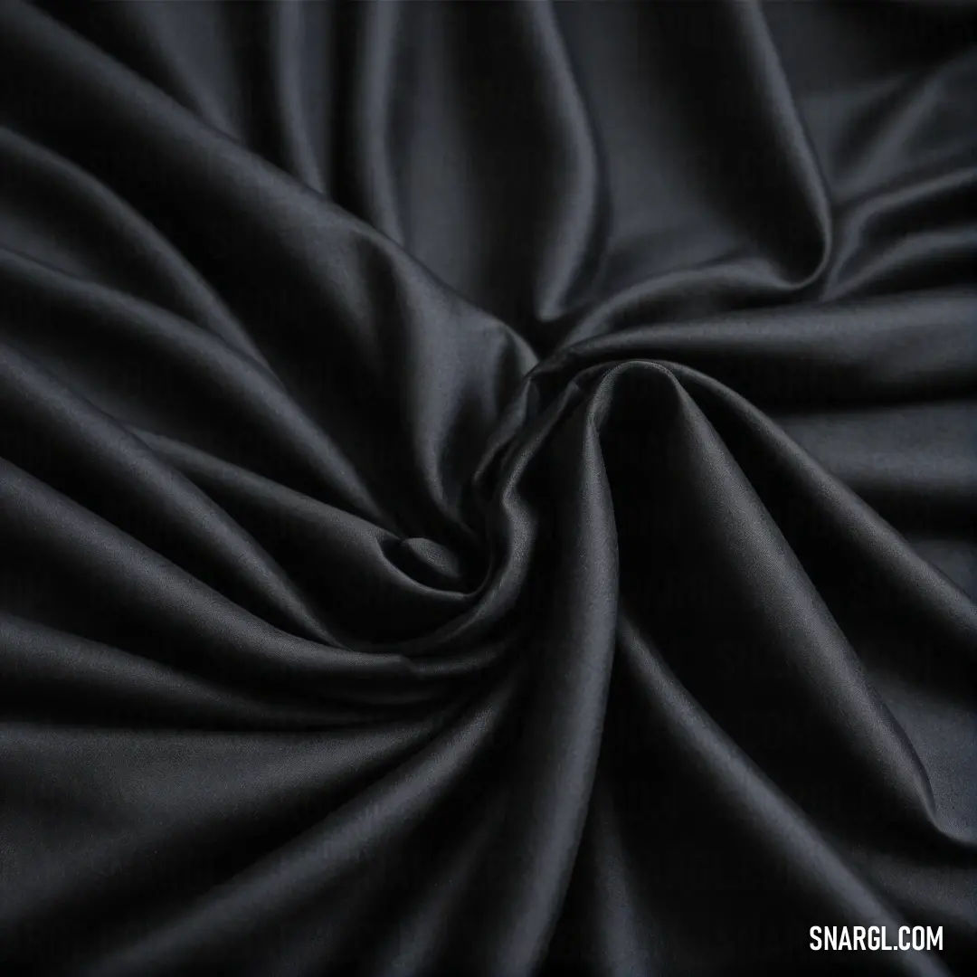 An elegant piece of black fabric is accented by a subtle line of contrasting fabric on its side against a dark backdrop, showcasing the rich depth of PANTONE 519 color in a refined setting.