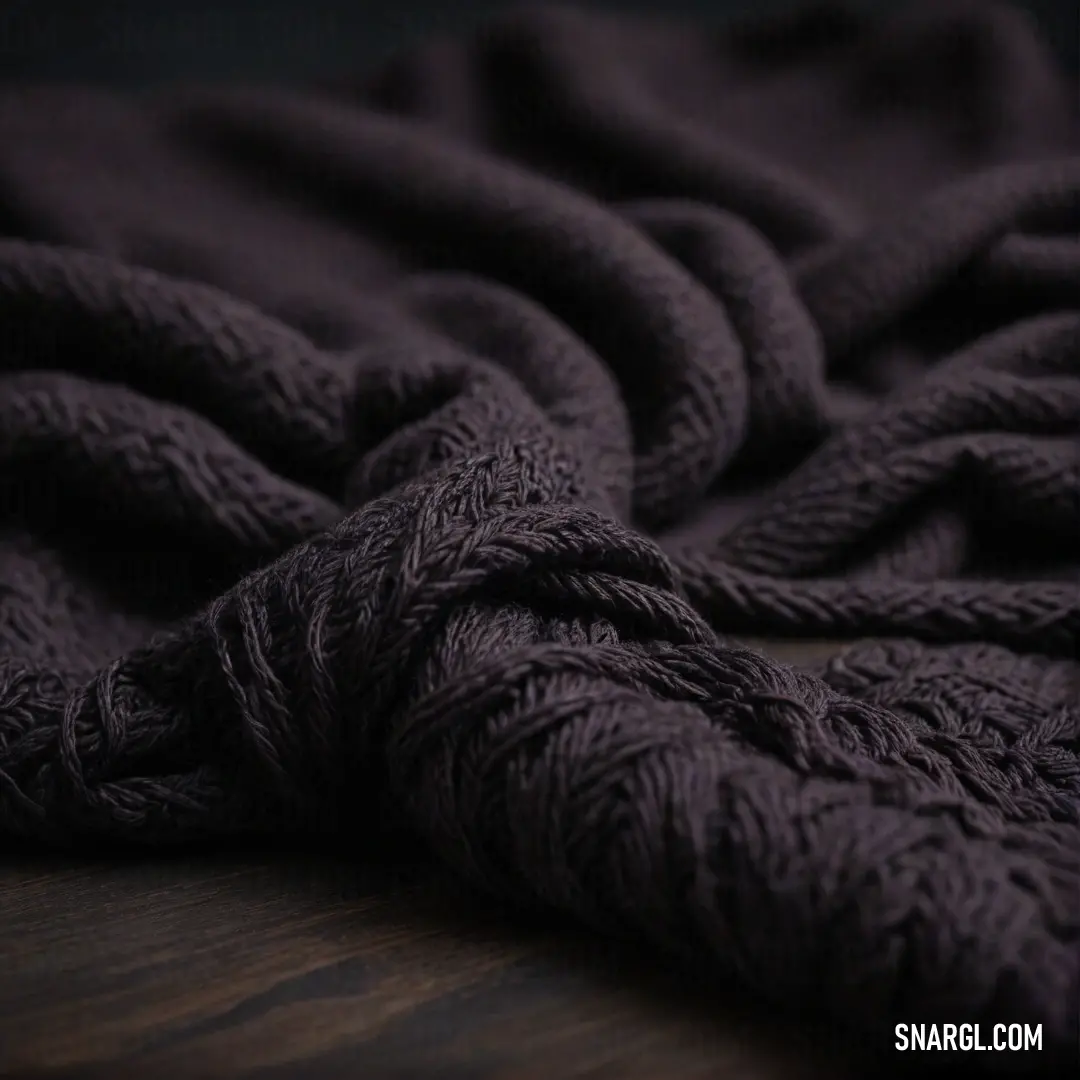 A close-up view of a plush purple blanket sprawled on a wooden floor, contrasted against a dark backdrop, showcasing the multifaceted beauty of CMYK 65,95,9,40 colors in an inviting setting.