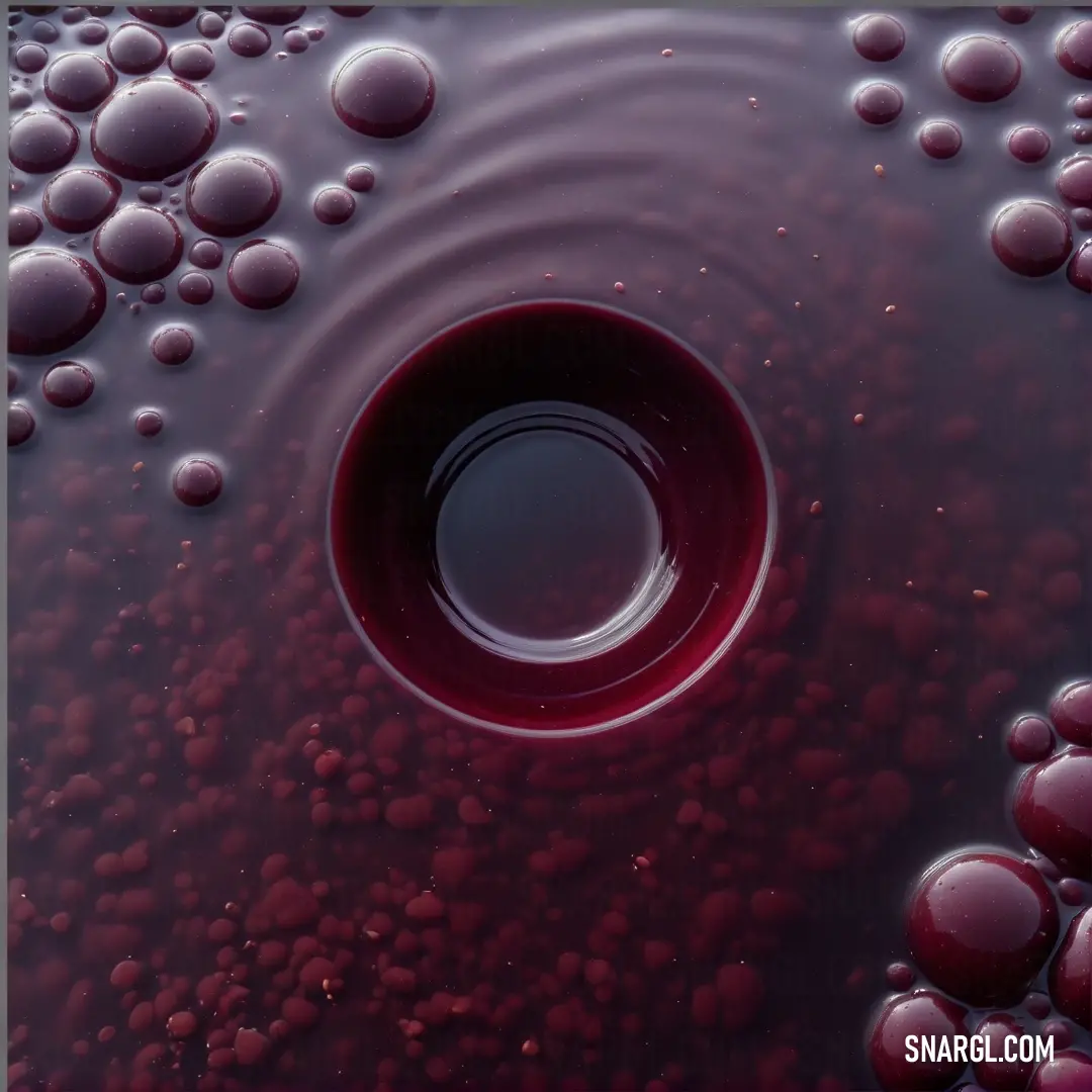 A mesmerizing view of red liquid filled with tiny bubbles floats delicately in a clear bowl of water, creating a striking visual of color interplay that captivates the senses.