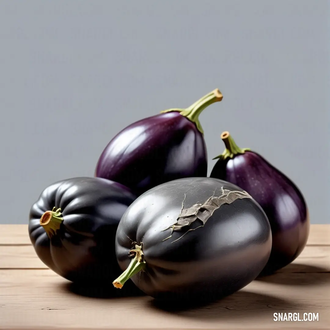 Three glossy black eggplants artfully arranged on a wooden table, contrasting beautifully with a soft gray backdrop, creating a stunning visual display highlighting the elegance of PANTONE 519 color.