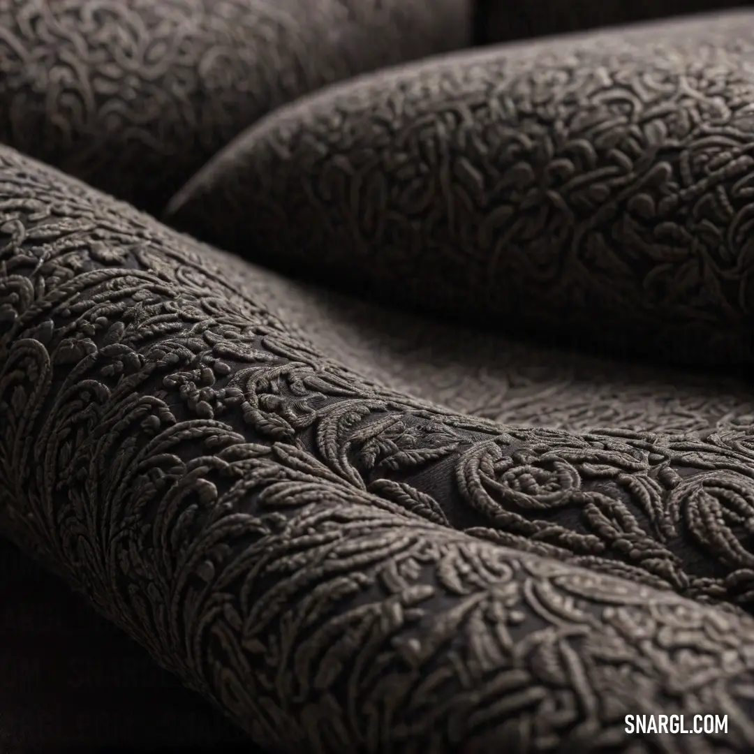 A vibrant close-up of a plush pillow revealing an intricate decorative pattern on its back side, set against a deep black background that emphasizes the pillow's rich textures and colors.