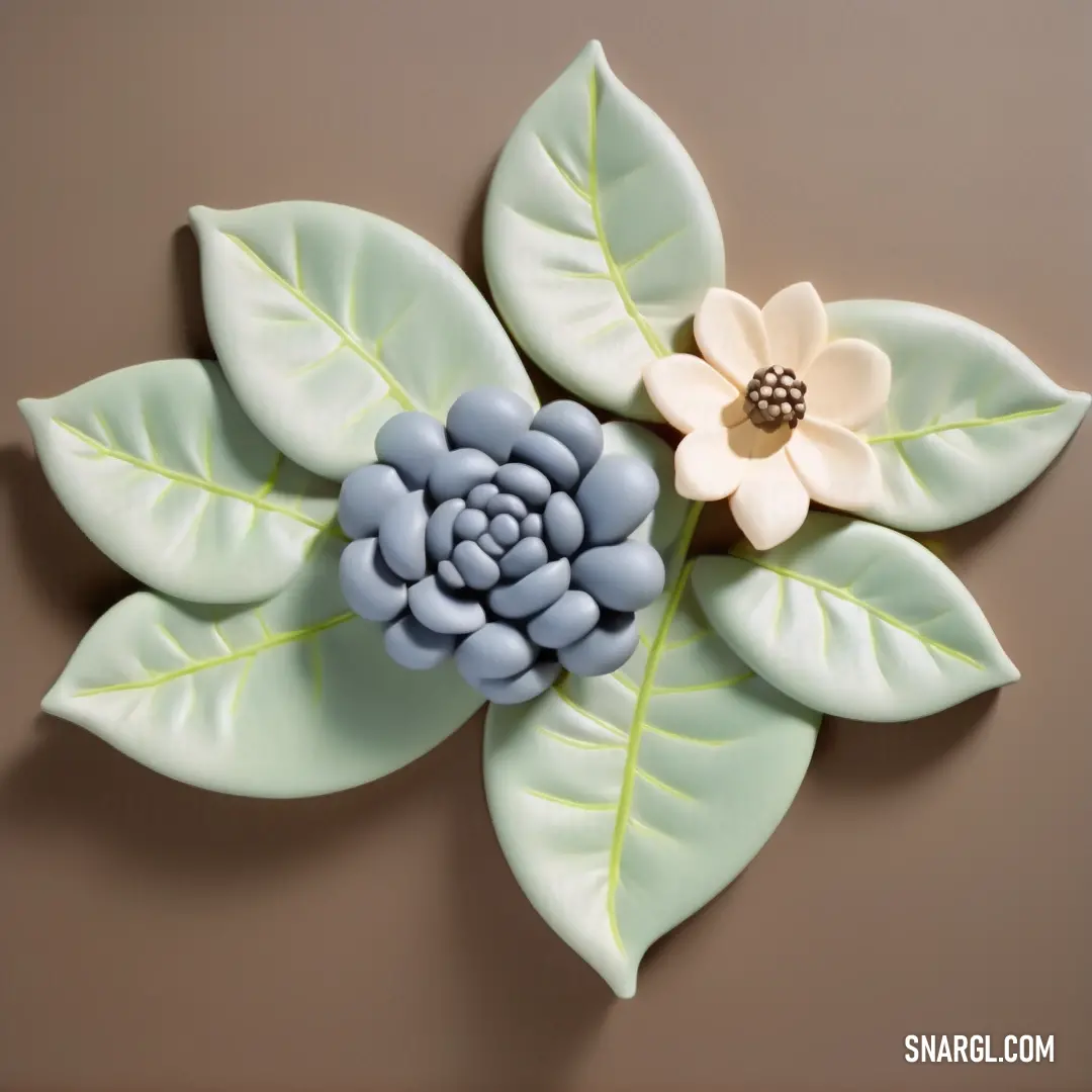 Ceramic flower with green leaves and a brown background with a brown center and a white center