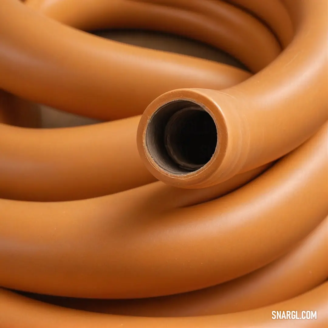 A detailed close-up of a hose with a brown end resting on a clean table surface, with a white background. The simplicity of the scene allows the soft PANTONE 617 color of the hose to stand out.