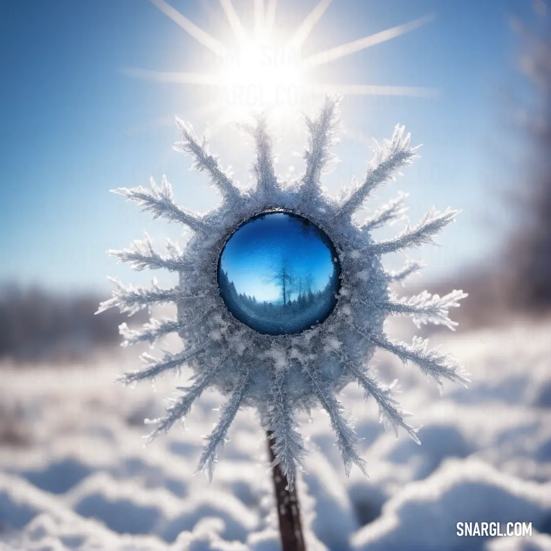 Snowflake with a blue ball in the middle of it in the snow. Color CMYK 9,8,0,1.