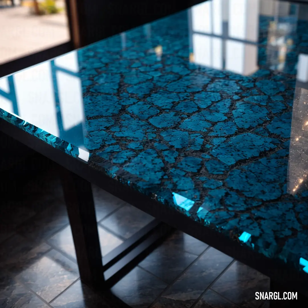 Blue table with a black metal base and a glass top with a reflection of a building in the window. Example of CMYK 89,22,34,65 color.