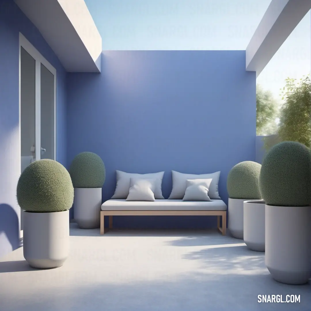 Room with a couch and some plants in it and a blue wall behind it. Example of #6C73A5 color.