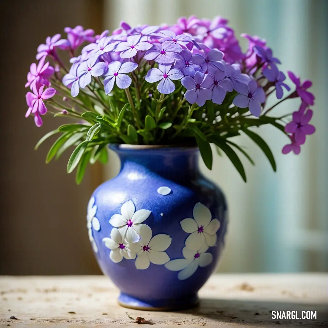 A stunning blue vase filled with vibrant purple flowers, elegantly placed on a wooden table. Natural sunlight streams through a nearby window, illuminating delicate curtains that frame the serene indoor scene, creating a tranquil atmosphere.