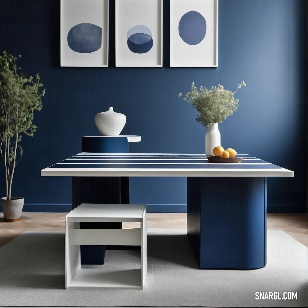 Blue room with a table and two pictures on the wall and a vase with fruit on it and a vase with flowers. Color PANTONE Cool Gray 1.
