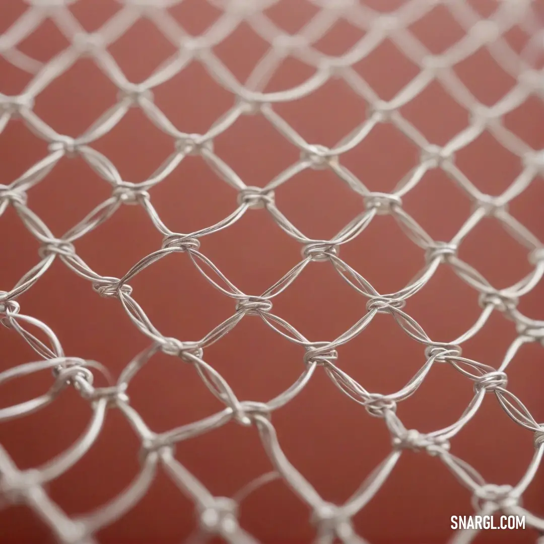 This close-up captures a robust metal mesh fence, illuminated by a vibrant red backdrop, juxtaposing strength with a splash of color that energizes the scene.