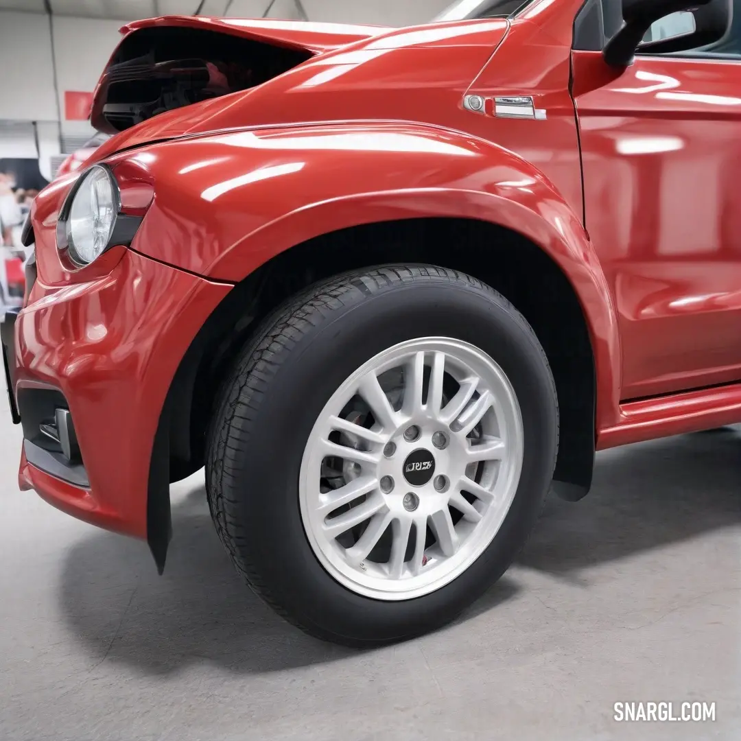 A striking red car rests on its side, featuring a sleek design with white rims and a bold black tire rim, capturing hearts with its sporty look. This striking color combination exudes a sense of energy and style.