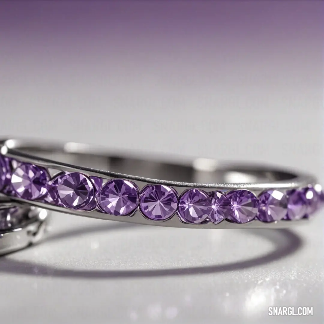 A pair of rings, each featuring a purple stone, sits on a table, showcasing their vibrant color and intricate details. The soft, neutral background allows the rings to stand out as elegant and sophisticated pieces of jewelry.