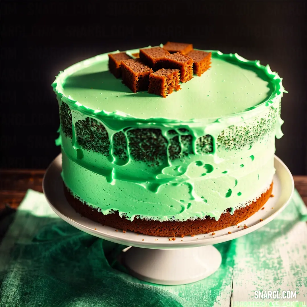 Cake with green frosting and a piece of chocolate on top of it on a plate on a table