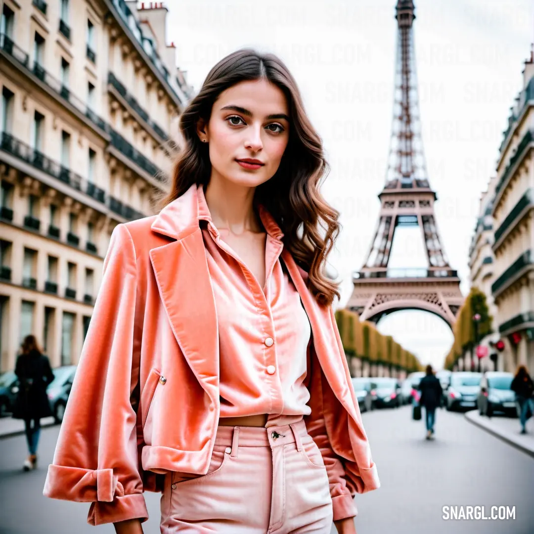 Woman in a pink top and pink pants stands in front of the eiffel tower in paris