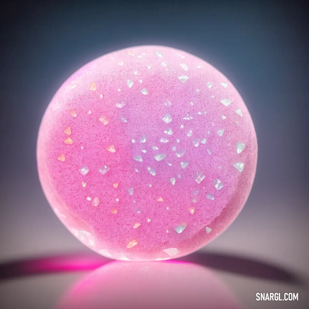 Pink bath ball with white glitter on it's surface and a shadow on the ground behind it