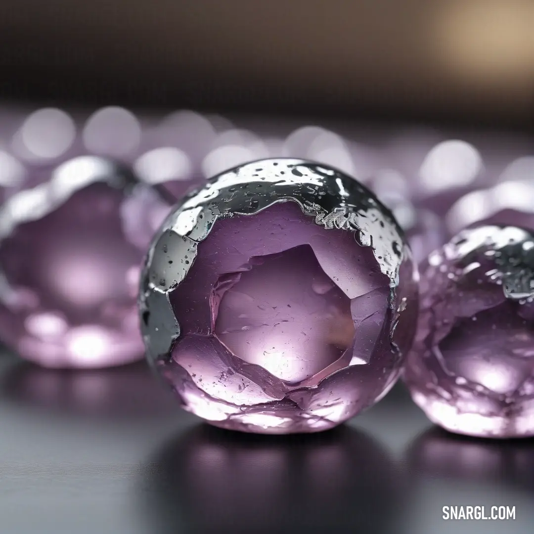 A collection of purple glass balls rests on a sleek table, their smooth surfaces catching the light. The deep purple hue of the glass contrasts beautifully with the simplicity of the table, creating a sense of elegance and refinement.