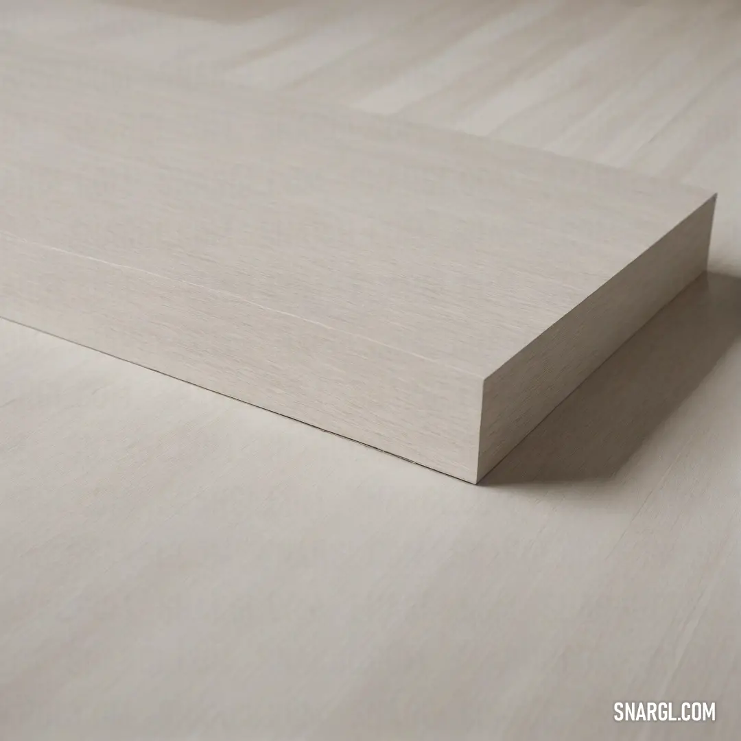 A pristine white sheet of plywood rests elegantly on a smooth white surface, showcasing a steady wooden edge. The simplicity evokes a sense of minimalism and subtle beauty in this clean, unadorned composition.