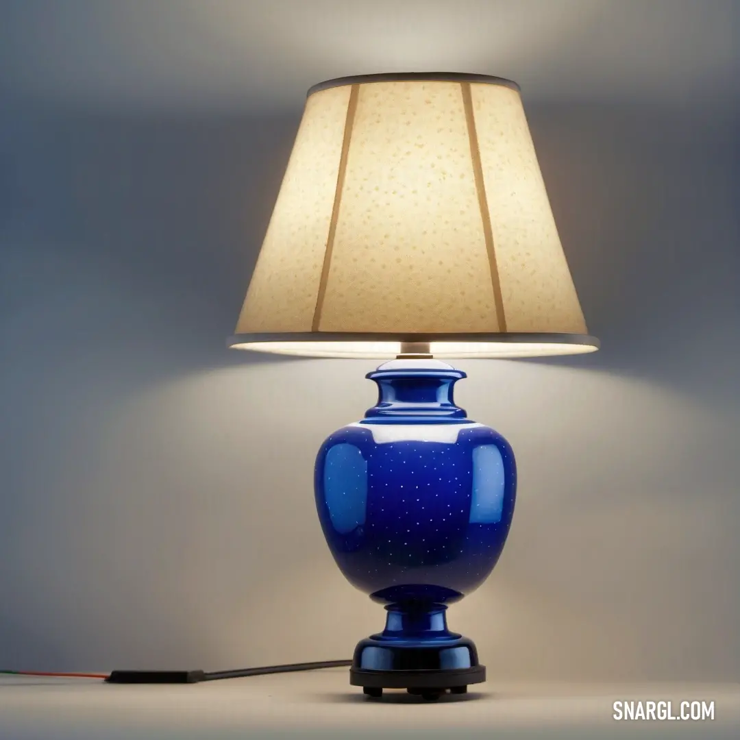 Peach color. Blue lamp with a white shade on it and a black cord plugged into it on a table