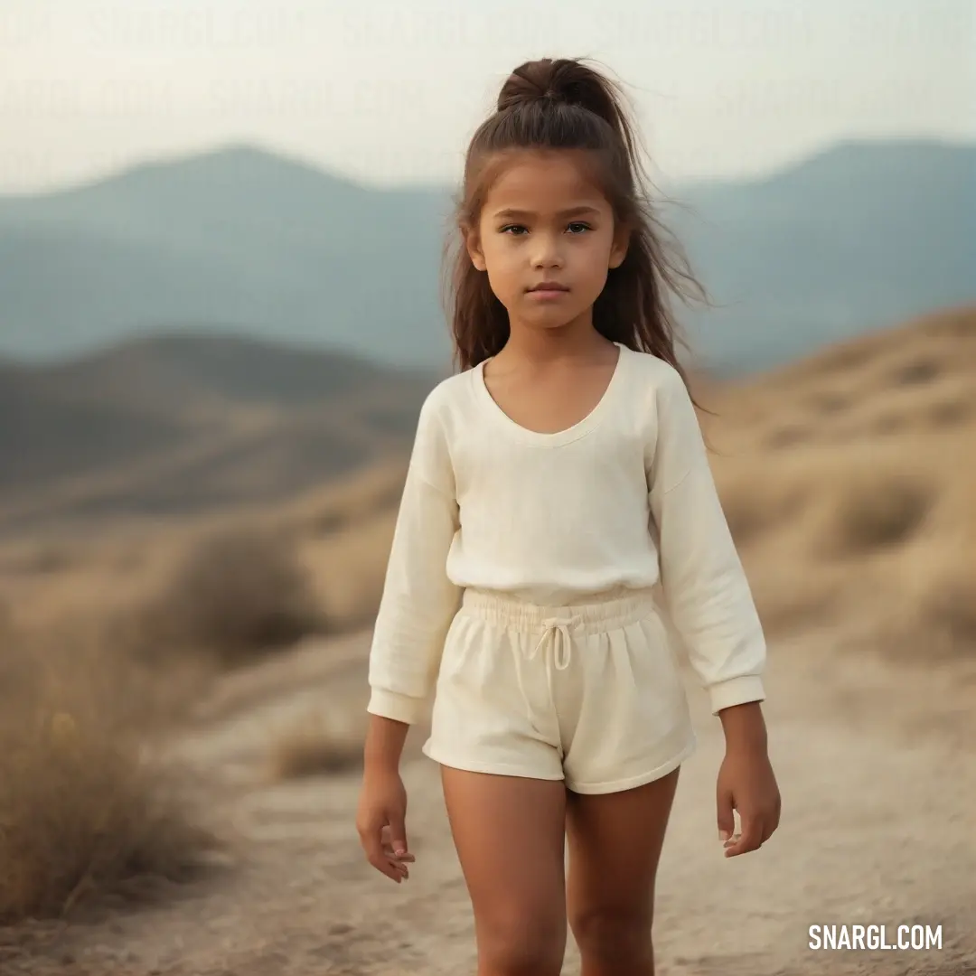 Little girl walking down a dirt road in the desert with mountains in the background. Color RGB 255,229,180.
