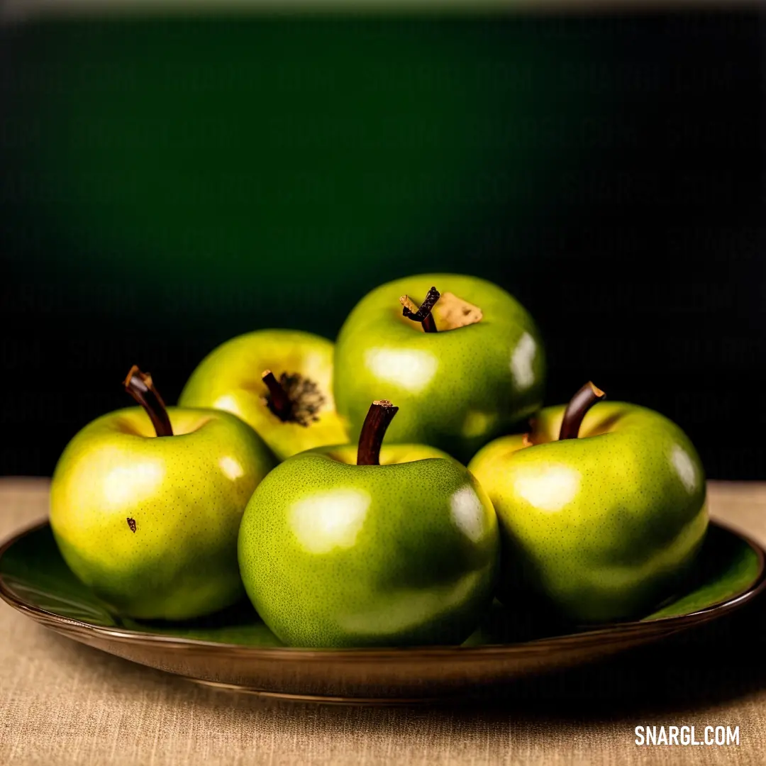 Plate of green apples on a table cloth with a green background behind it