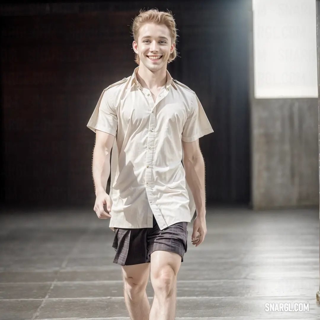 Man walking down a runway in a white shirt and black shorts with a smile on his face