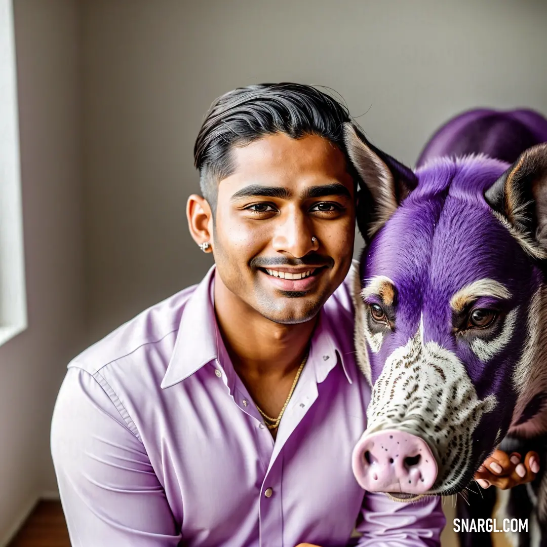 Man poses with a purple cow in a room with a window and a white wall behind him