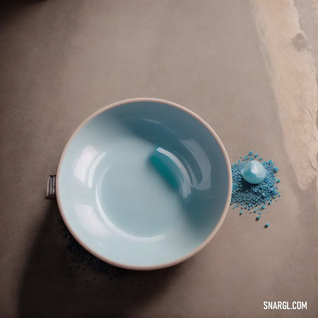 Bowl with a spoon in it and some blue powder in it on a table top next to a spoon
