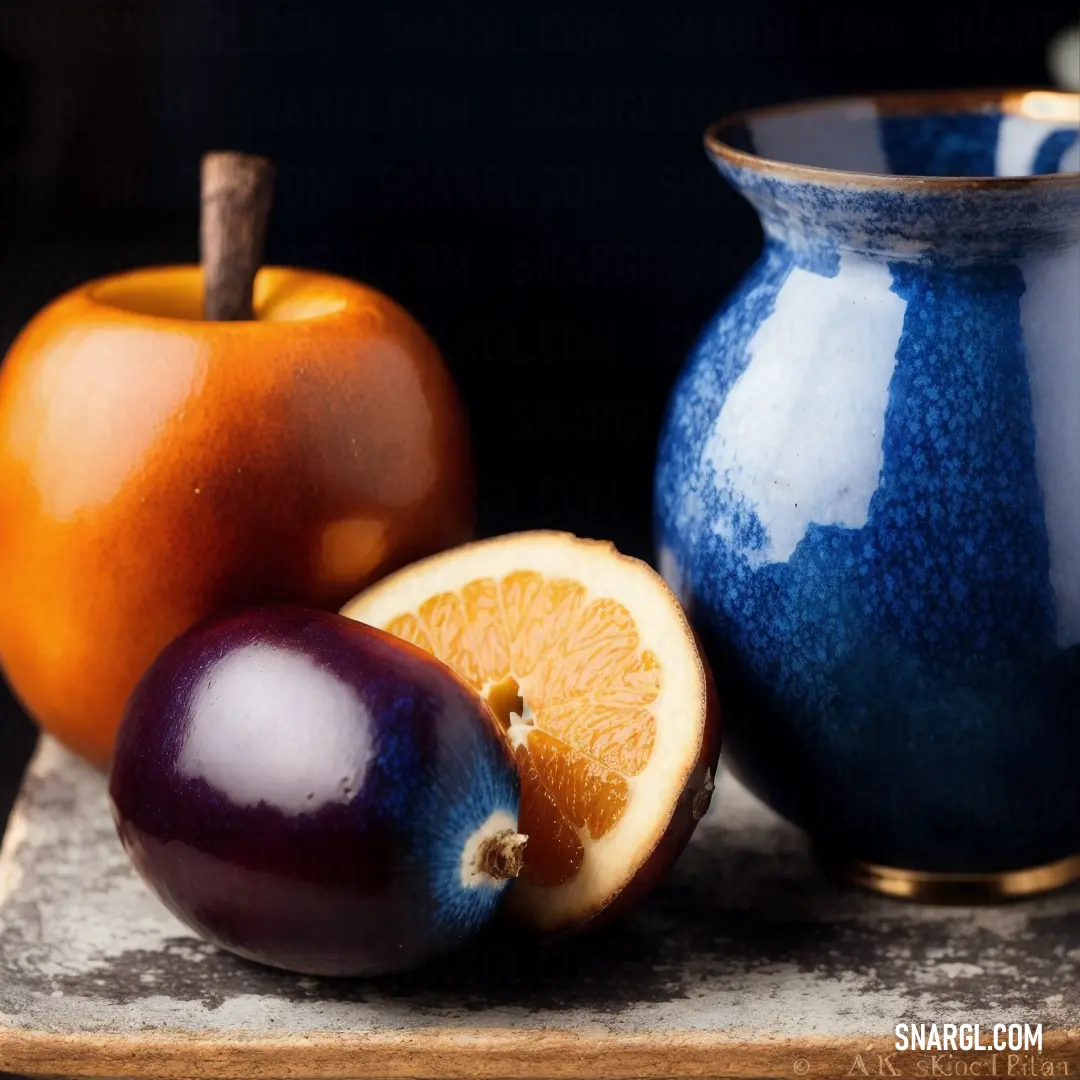 Blue vase next to a cut up orange and an apple on a table top with a knife