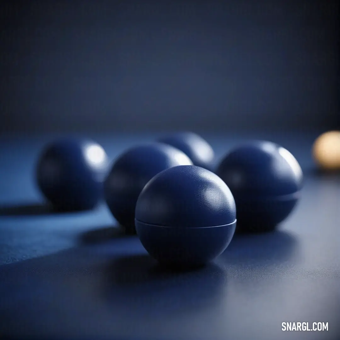 Group of blue balls on top of a table next to a candle and a wall light in the background. Example of #003153 color.