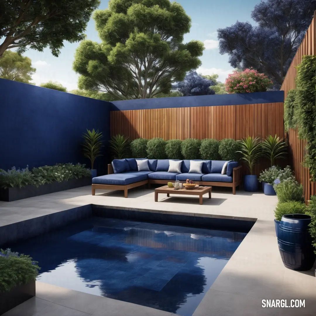 Pool with a couch and table next to it and a wooden fence behind it and a blue wall. Color Prussian blue.