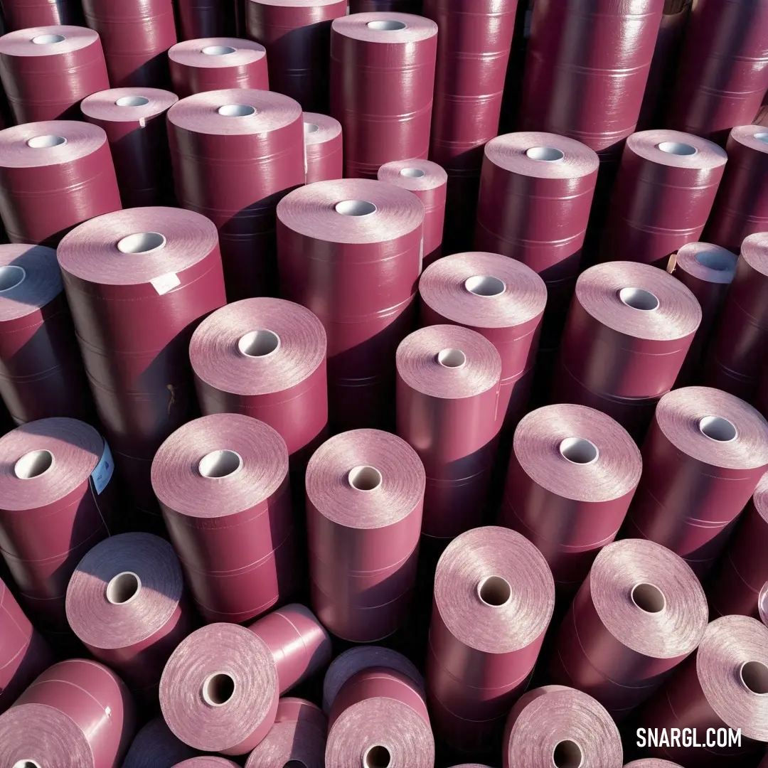 Puce color. Large group of rolls of pink colored yarn are stacked together in a pile and ready to be used