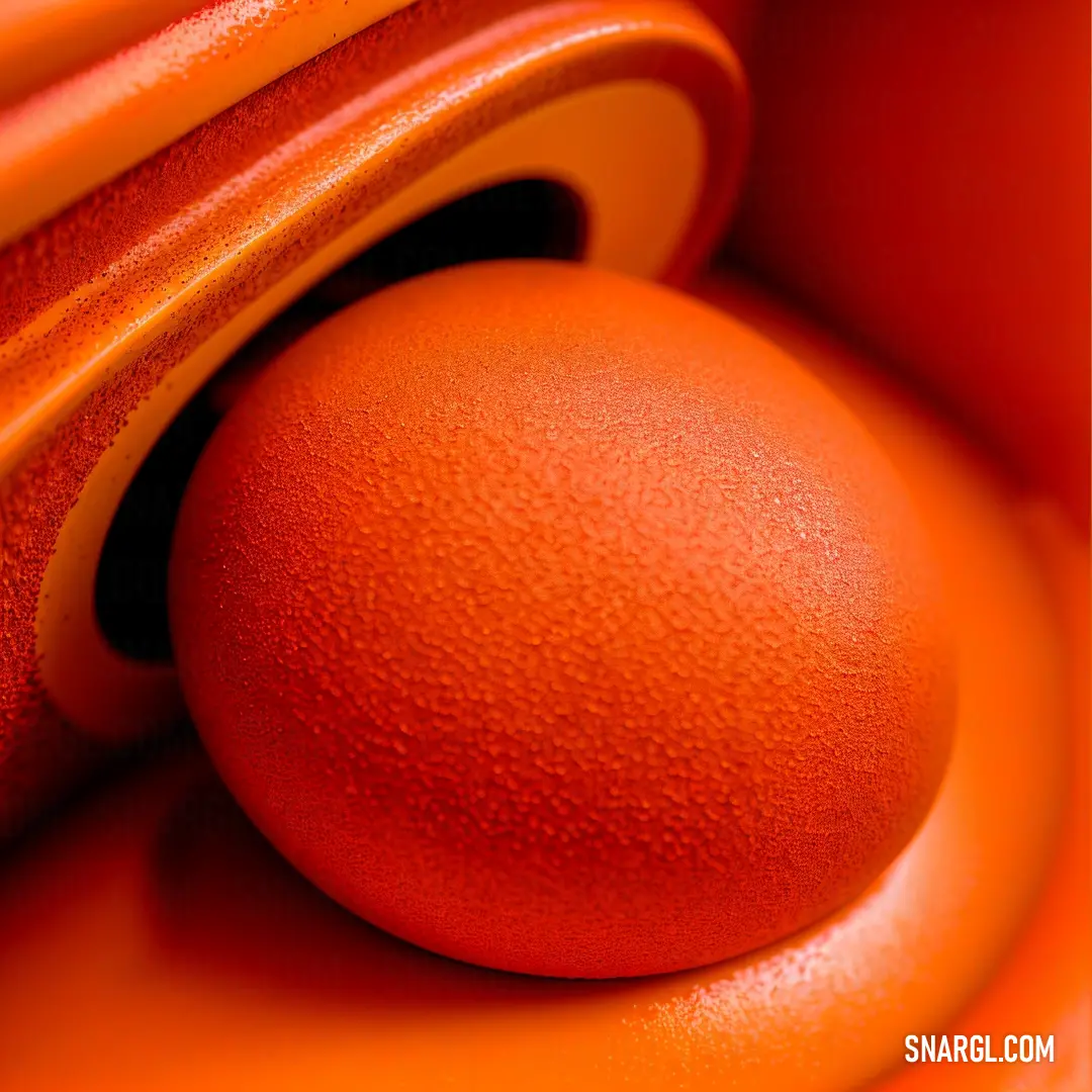 An orange object sits in the foreground, its bright color drawing attention. The blurry background creates a sense of depth, highlighting the richness of the color and the object's intriguing presence in the scene.