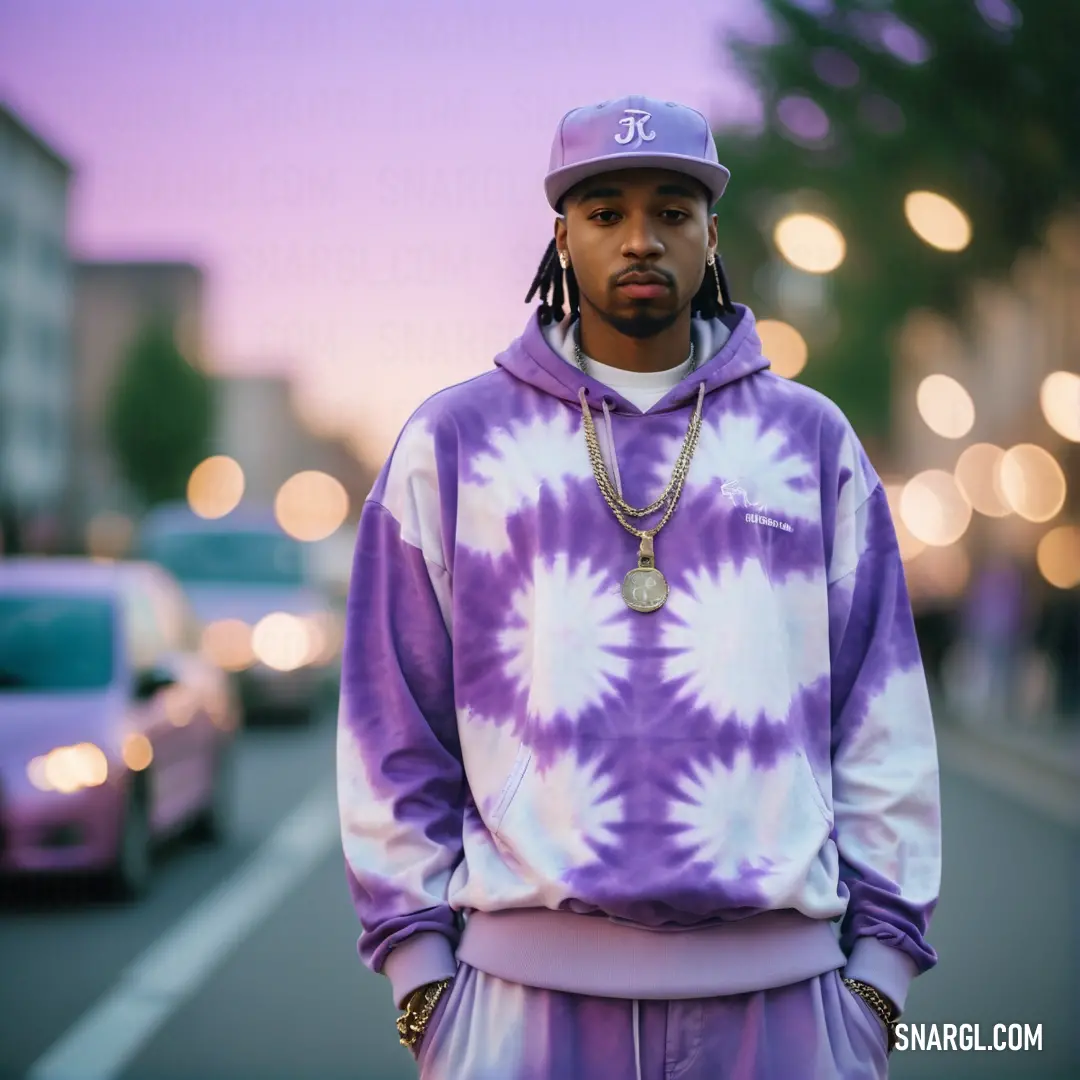 RAL 300 70 15 color. Man standing on a street with a tie dye hoodie on and a hat on his head and a car in the background