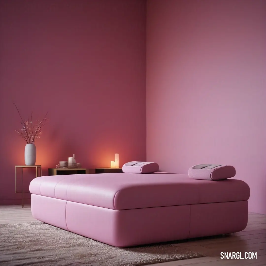 Pink couch in a living room next to a table with a vase on it and candles on the side. Color #EAA4D0.