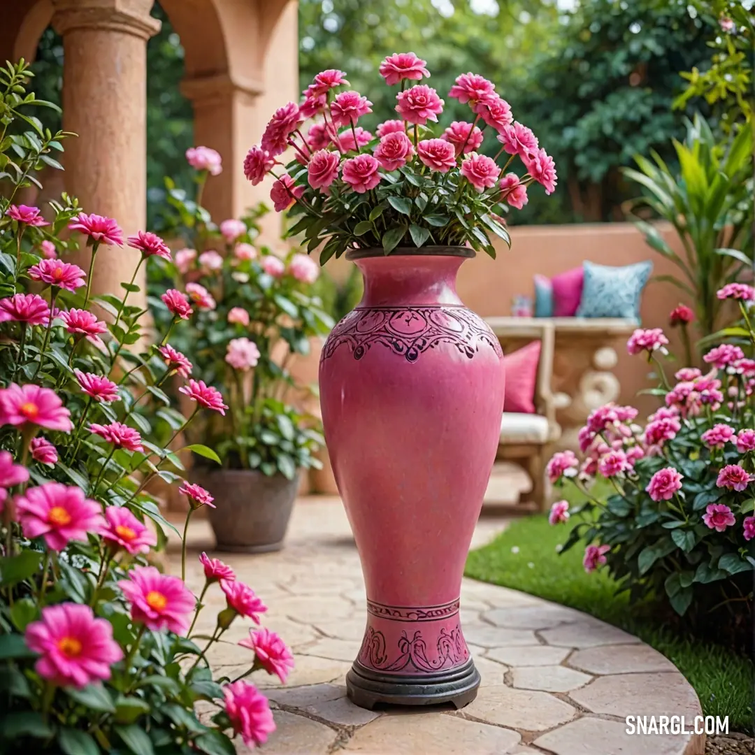 Pink vase with pink flowers in it on a stone walkway in a garden area with pink flowers and a bench. Color Raspberry pink.