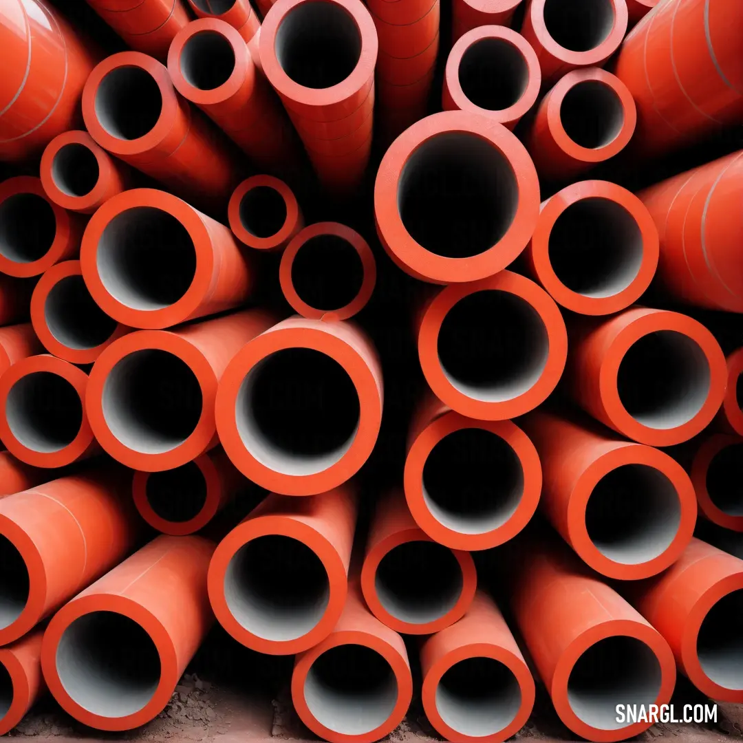 Pile of orange pipes stacked on top of each other in a pile on the ground with a brick floor. Example of Red Orange color.
