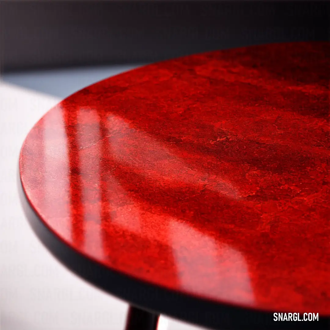 Red table with a black top and a white background with a shadow of a chair on the table