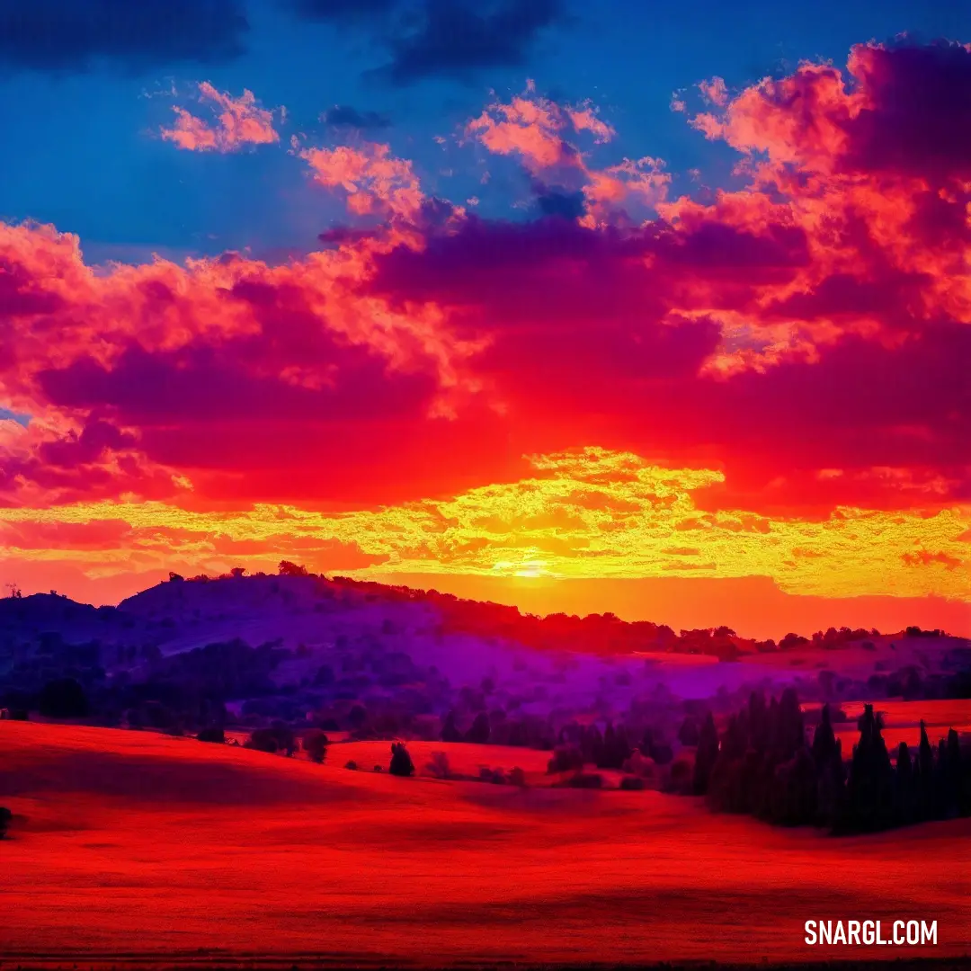 Sunset with a red sky and clouds over a field and mountains in the distance with trees and grass