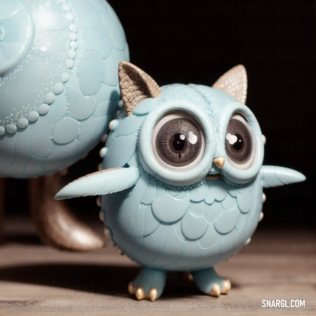 Blue owl figurine with big eyes and a cat's head on it's back