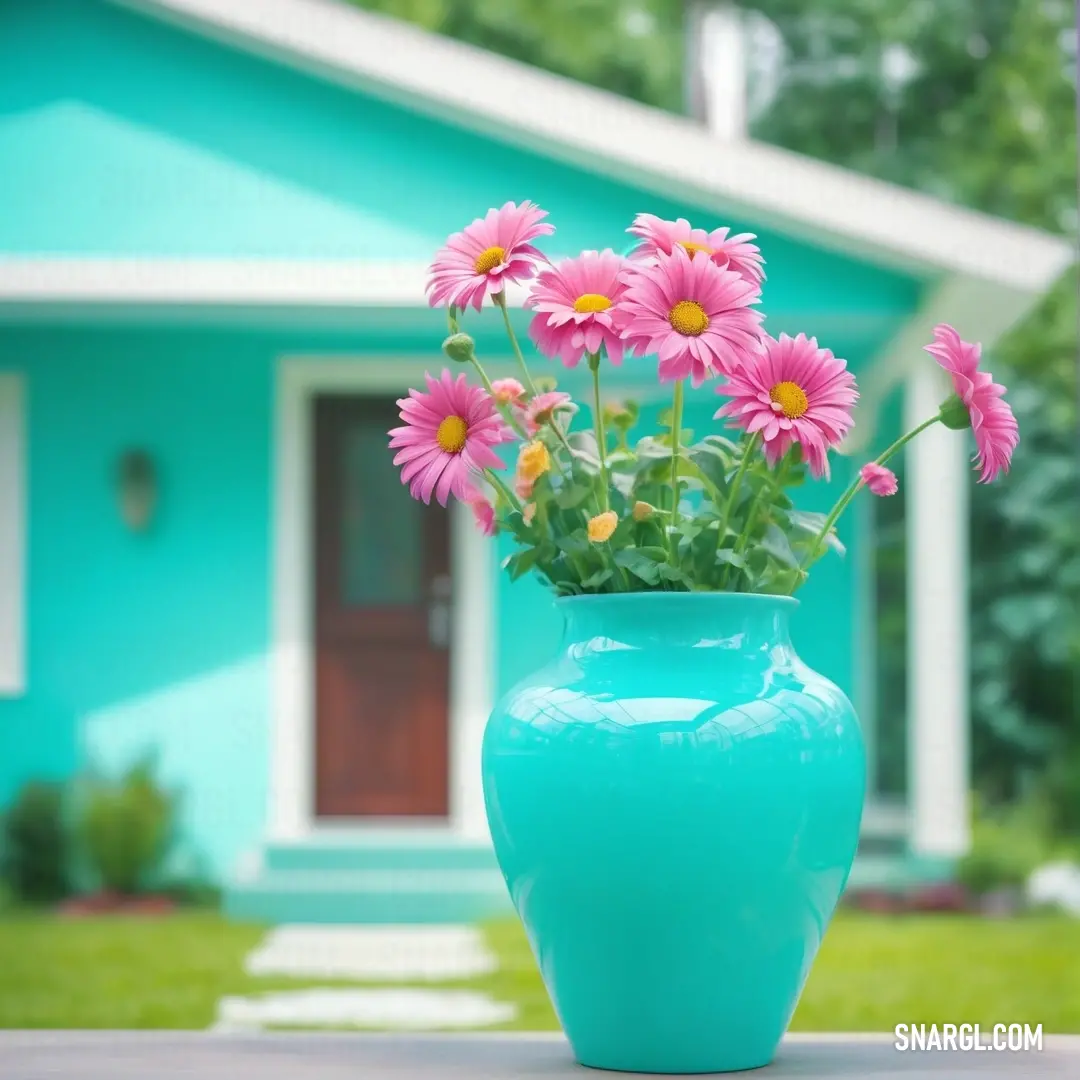 Robin Egg Blue color. Blue vase with pink flowers in it on a table outside a house with a blue door and green grass
