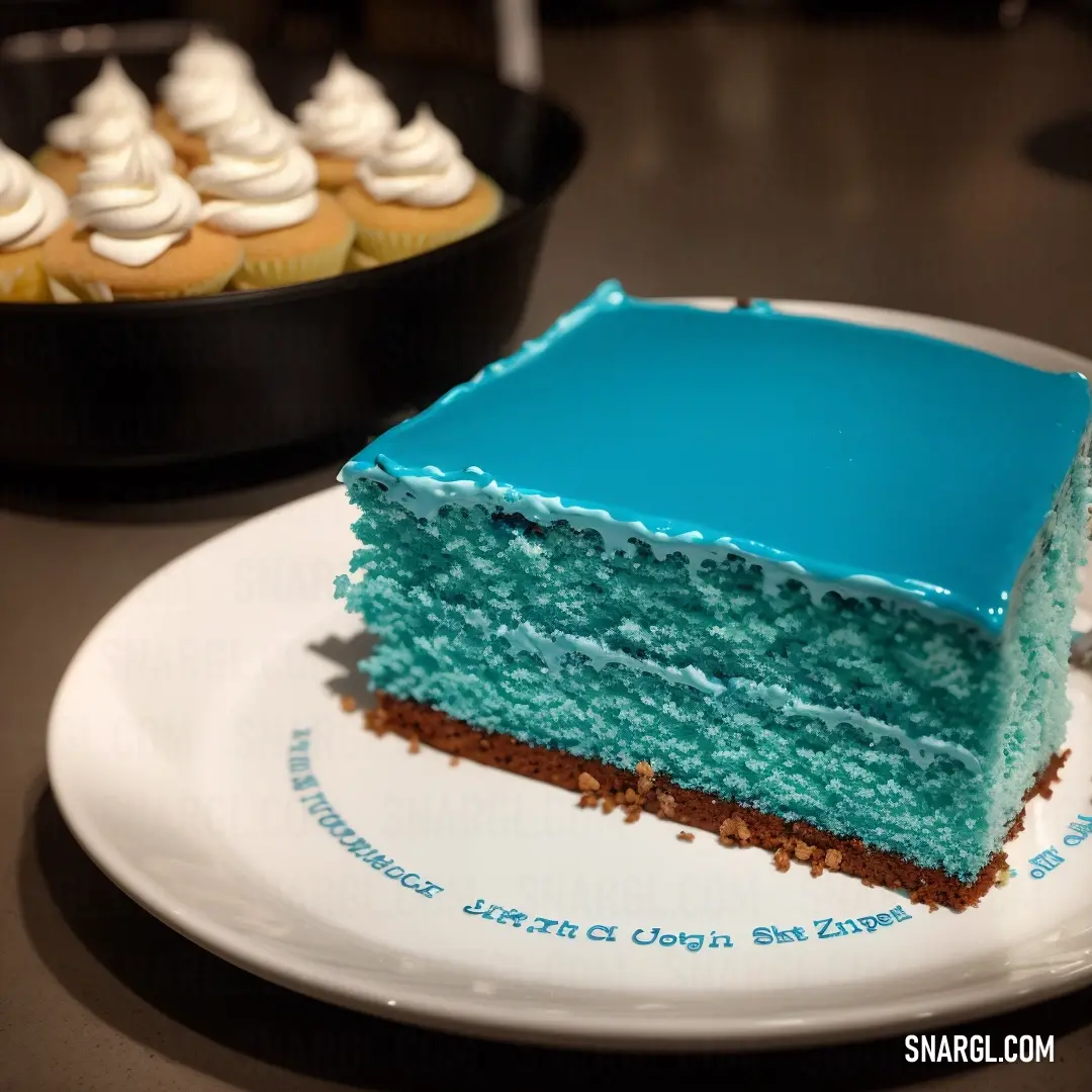 Piece of cake on a plate with a cupcake in the background on a table with a plate of cupcakes. Color Robin Egg Blue.