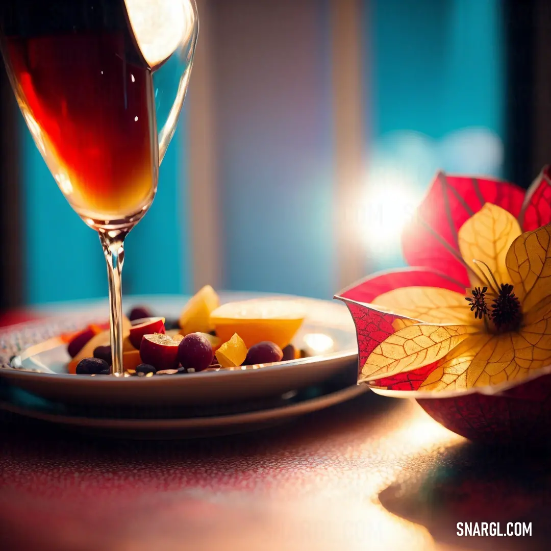 Plate of food and a glass of wine on a table with a flower decoration on it and a plate of fruit