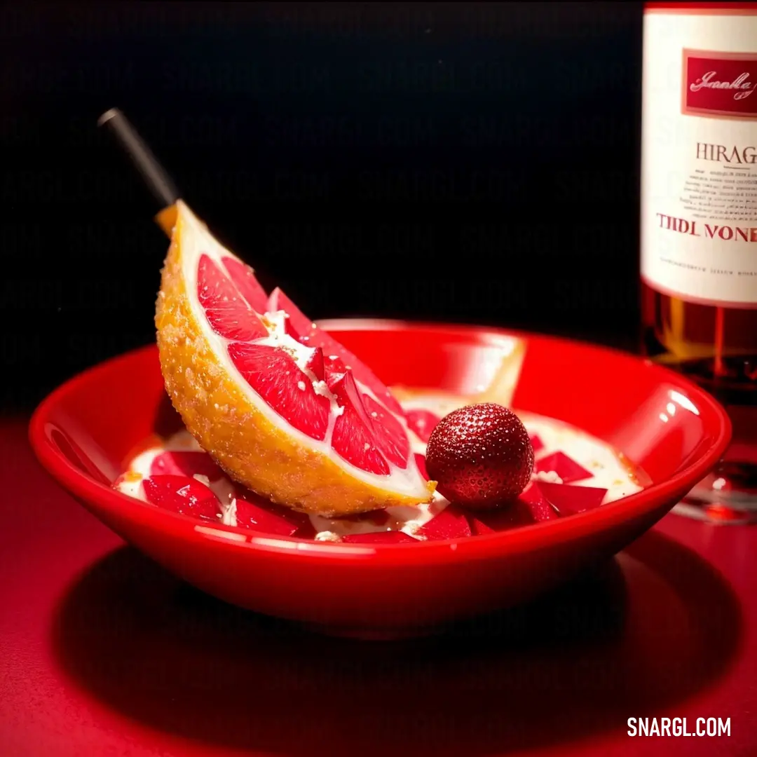 Red bowl with a grapefruit and a bottle of wine on a table with a red table cloth