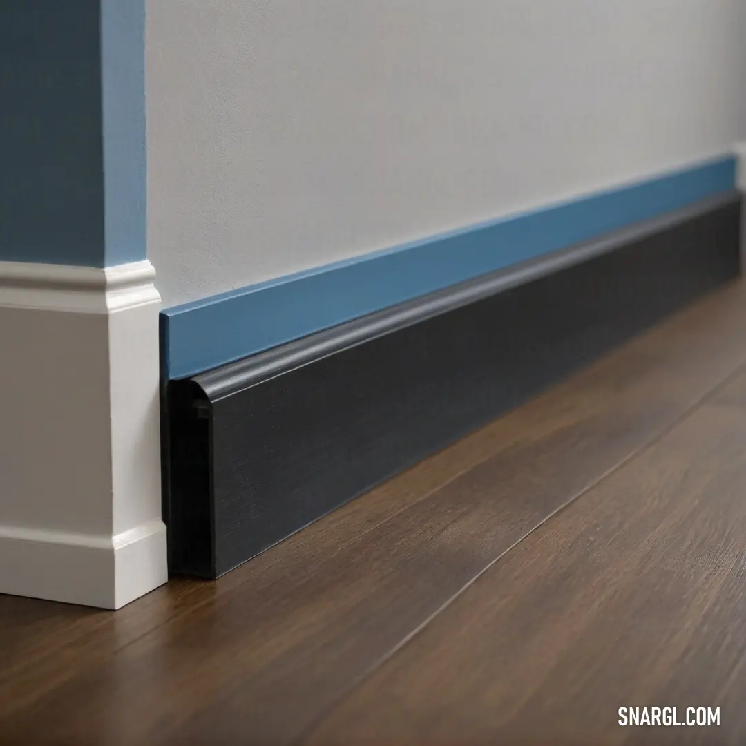 An intimate view of a rich wooden floor, highlighted by a vibrant blue strip adorning the wall above. A pristine white baseboard completes this captivating detail, showcasing the unique interplay of colors in this cozy setting.