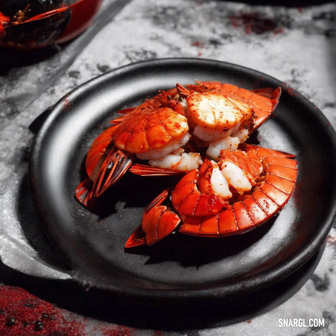 Plate of cooked lobsters on a table with a bowl of sauce in the background