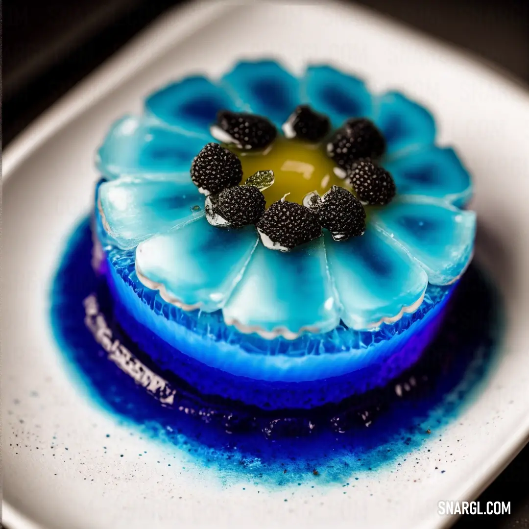 Blue cake with blackberries on top of it on a plate