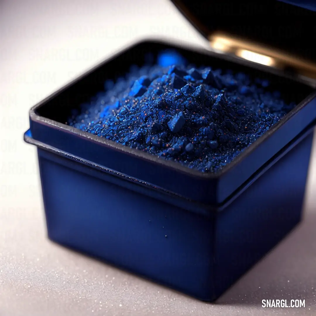 Blue container filled with blue powder on a table next to a gold lid and a black container