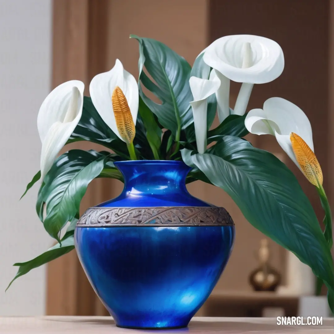 Royal blue color example: Blue vase with white flowers in it on a table next to a mirror and a door way in the background