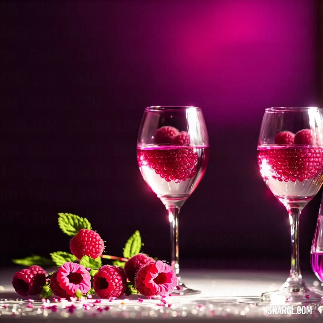 Couple of wine glasses filled with liquid and some raspberries on a table with a purple background